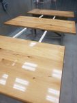 Spray application of a clear protective finish on custom solid wood tabletops. Solid wood tabletops receiving a spray-applied clear finish for a smooth, durable surface at Leone’s Custom Coatings.